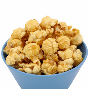 Blue bowl filled with caramel coated popcorn against a white background.