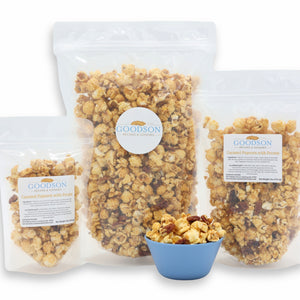 Goodson popcorn packages of varying sizes with a bowl of popcorn on a white background