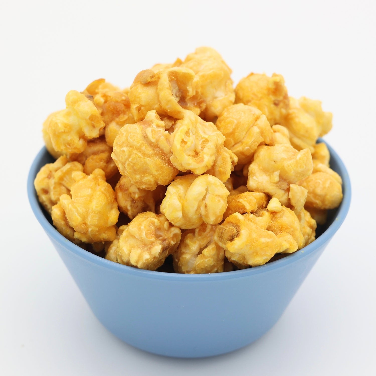 Blue bowl filled with caramel and white cheddar covered popcorn against a white background.