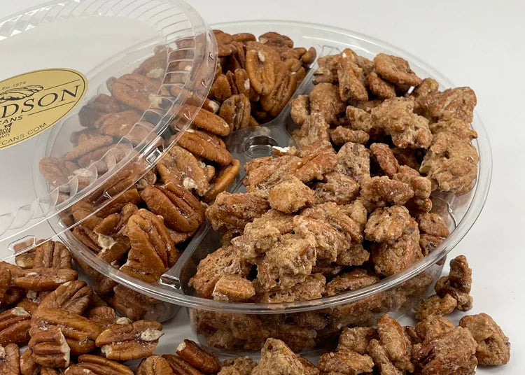 Assorted pecans in a clear plastic container on a white background