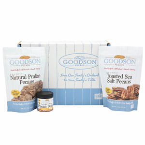 Two packages of Goodson Pecans Natural Praline Pecans, and Toasted Sea Salt Pecans, a small jar of Goodson Pecans Pecan Butter, and a Goodson Pecans box against a white background.
